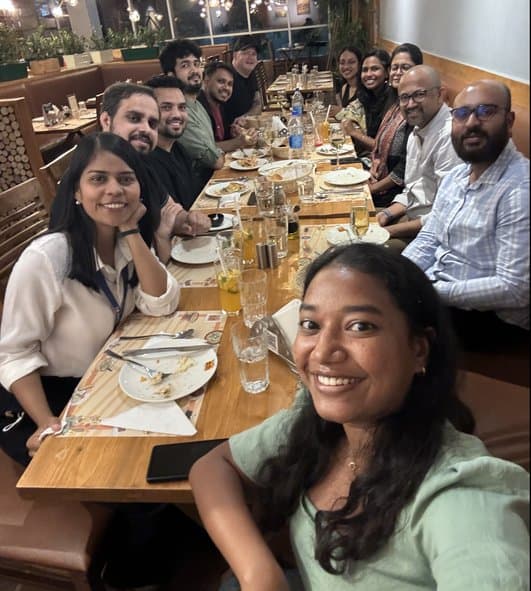 The team seated along a long dinner table, smiling at the camera