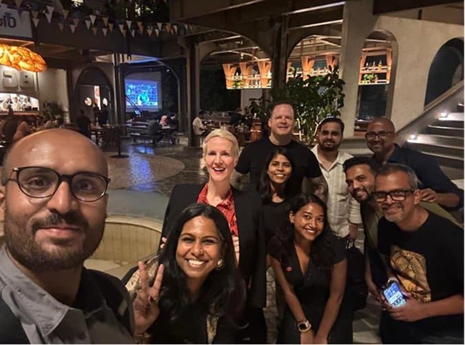 A group selfie of the team smiling together in a restaurant